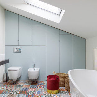 Immagine di una stanza da bagno padronale minimal di medie dimensioni con vasca freestanding, WC sospeso, pareti bianche, pavimento con piastrelle a mosaico e pavimento multicolore