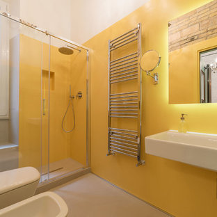 Immagine di una stanza da bagno con doccia eclettica con doccia alcova, WC sospeso, pareti gialle, pavimento in cemento, lavabo sospeso, pavimento beige e porta doccia scorrevole
