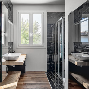 Immagine di una grande stanza da bagno con doccia minimal con ante nere, piastrelle nere, lavabo a bacinella, top in legno, pavimento marrone, porta doccia a battente, pareti bianche, pavimento in gres porcellanato, top beige e mobile bagno sospeso