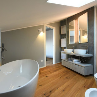 Foto di una grande stanza da bagno padronale contemporanea con nessun'anta, ante grigie, vasca freestanding, WC sospeso, piastrelle grigie, pareti grigie, lavabo a bacinella, pavimento marrone, top grigio, due lavabi e mobile bagno sospeso