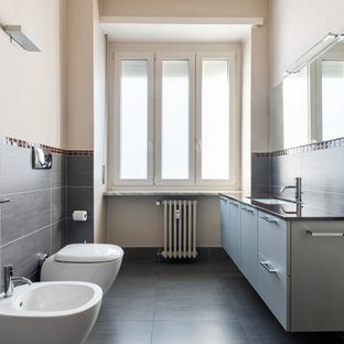 Foto di una stanza da bagno con doccia minimal di medie dimensioni con ante lisce, ante grigie, WC sospeso, piastrelle nere, piastrelle in gres porcellanato, pareti beige, pavimento in gres porcellanato, lavabo sottopiano, pavimento nero e top nero