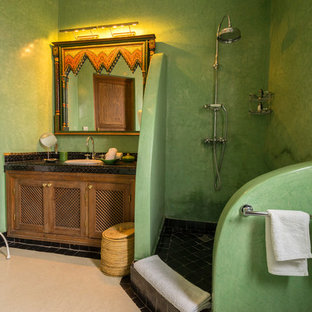 Immagine di una stanza da bagno con doccia mediterranea con pareti verdi, doccia aperta, ante con riquadro incassato, ante in legno scuro, doccia ad angolo, lavabo da incasso, pavimento beige e top nero