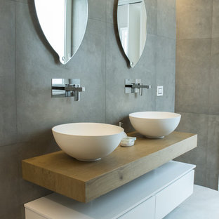 Ispirazione per una stanza da bagno padronale contemporanea con piastrelle grigie, piastrelle in gres porcellanato, lavabo a bacinella, ante lisce, ante bianche, pareti grigie, top in legno, pavimento bianco e top marrone