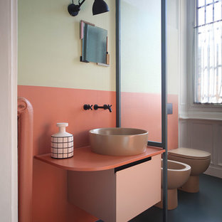 Foto di una stanza da bagno eclettica di medie dimensioni con piastrelle arancioni, lavabo a bacinella, pavimento nero, ante lisce, WC monopezzo, pareti multicolore e pavimento in cemento