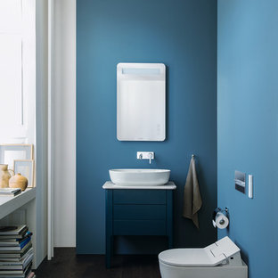 Foto di una piccola stanza da bagno minimal con ante blu, lavabo a bacinella, top in quarzo composito, ante lisce, WC sospeso, pareti blu, parquet scuro, pavimento marrone e top bianco