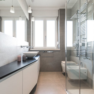 Ispirazione per una stanza da bagno design di medie dimensioni con pareti grigie, pavimento in gres porcellanato, ante lisce, ante bianche, bidè, lavabo a bacinella, porta doccia a battente, top nero, piastrelle beige, piastrelle grigie e pavimento beige