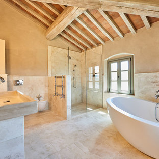 Esempio di una stanza da bagno padronale mediterranea con vasca freestanding, doccia a filo pavimento, WC sospeso, piastrelle beige, pareti beige, lavabo rettangolare, pavimento beige e doccia aperta