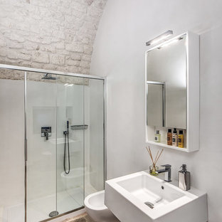 Immagine di una stanza da bagno mediterranea con doccia alcova, WC sospeso, pareti bianche, lavabo sospeso, pavimento marrone e porta doccia scorrevole