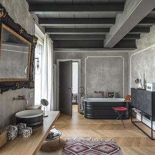 Immagine di una stanza da bagno industriale con vasca freestanding, piastrelle grigie, pareti grigie, pavimento in legno massello medio, lavabo a bacinella, top in legno, pavimento beige e top beige