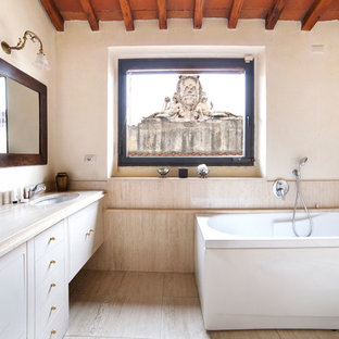 Esempio di una stanza da bagno mediterranea con ante lisce, ante bianche, vasca freestanding, vasca/doccia, piastrelle beige, pareti bianche, lavabo sottopiano, pavimento beige, doccia aperta e top beige
