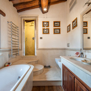 Ispirazione per una stanza da bagno padronale country con ante con bugna sagomata, ante in legno bruno, vasca da incasso, doccia alcova, WC sospeso, pareti beige, parquet scuro, lavabo sottopiano, top in cemento, pavimento marrone, porta doccia a battente e top grigio