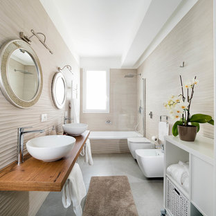 Esempio di una stanza da bagno con doccia con vasca ad alcova, vasca/doccia, bidè, piastrelle beige, pareti beige, lavabo a bacinella, top in legno, pavimento grigio, porta doccia a battente e top marrone
