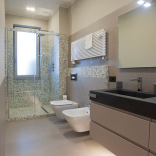 Idee per una stanza da bagno con doccia minimal di medie dimensioni con ante lisce, ante grigie, doccia alcova, WC sospeso, piastrelle grigie, piastrelle in gres porcellanato, pareti grigie, pavimento in gres porcellanato, lavabo integrato, pavimento grigio, porta doccia a battente, top nero, due lavabi, mobile bagno sospeso e panca da doccia