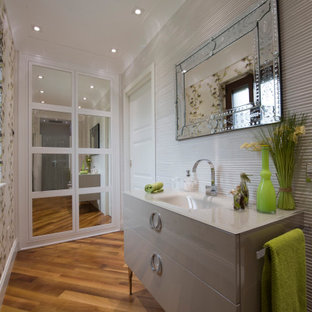 Foto di una stanza da bagno con doccia design di medie dimensioni con ante lisce, ante grigie, piastrelle grigie, pareti beige, pavimento in legno massello medio, lavabo integrato, pavimento marrone e top grigio