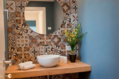 Foto di una piccola stanza da bagno design con ante in legno chiaro, piastrelle multicolore, top in legno, pareti blu e pavimento in laminato