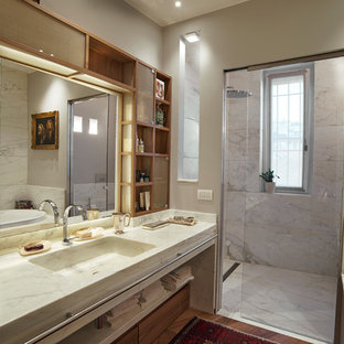 Foto di un'ampia stanza da bagno padronale tradizionale con ante di vetro, vasca da incasso, doccia a filo pavimento, WC monopezzo, piastrelle bianche, piastrelle di marmo, pareti beige, pavimento in legno massello medio, lavabo integrato, top in marmo, pavimento marrone, porta doccia scorrevole, top bianco e ante in legno scuro