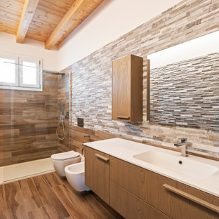Immagine di una piccola stanza da bagno con doccia moderna con ante in legno scuro, doccia aperta, bidè, piastrelle multicolore, piastrelle di pietra calcarea, lavabo da incasso, top in superficie solida, doccia aperta e top bianco
