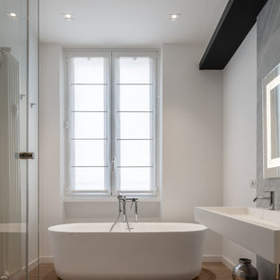 Foto di una stanza da bagno padronale minimal di medie dimensioni con nessun'anta, vasca freestanding, piastrelle grigie, lastra di pietra, pareti bianche, lavabo sospeso, top in superficie solida, top bianco e pavimento marrone