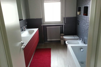 Esempio di una stanza da bagno padronale minimal di medie dimensioni con vasca da incasso, WC sospeso, piastrelle grigie, piastrelle in gres porcellanato, pareti bianche, pavimento in gres porcellanato e lavabo integrato