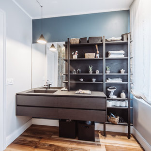 Foto di una stanza da bagno minimal con consolle stile comò, ante in legno bruno, pareti blu, pavimento in legno massello medio, lavabo integrato, pavimento marrone e top marrone