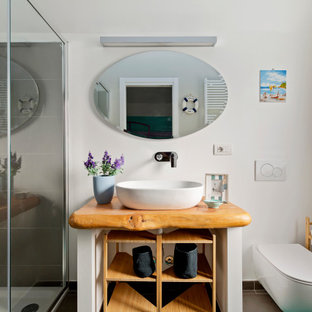 Ispirazione per una stanza da bagno con doccia design di medie dimensioni con ante bianche, doccia alcova, WC sospeso, piastrelle grigie, piastrelle in gres porcellanato, pareti bianche, lavabo a bacinella, top in legno, pavimento marrone, porta doccia scorrevole e top beige