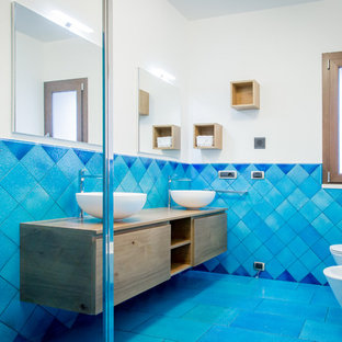 Immagine di una stanza da bagno stile marino con ante lisce, ante in legno scuro, doccia ad angolo, WC sospeso, pareti bianche, lavabo a bacinella, top in legno, pavimento blu, porta doccia a battente e top marrone