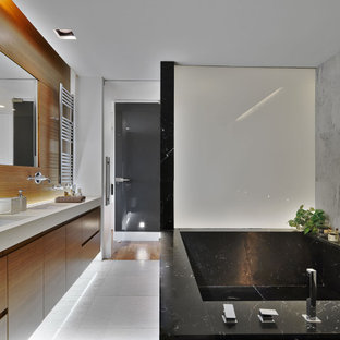 Foto di una grande stanza da bagno padronale minimal con ante lisce, ante in legno scuro, vasca ad angolo, piastrelle grigie, piastrelle in gres porcellanato, pareti bianche, pavimento in gres porcellanato, pavimento grigio, top grigio e mobile bagno sospeso