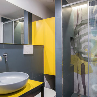 Ispirazione per una stanza da bagno con doccia contemporanea con consolle stile comò, ante gialle, WC sospeso, lavabo a bacinella, porta doccia scorrevole, top giallo e pareti grigie
