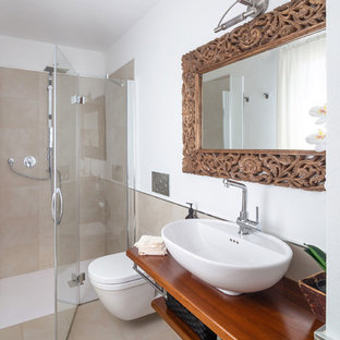 Foto di una stanza da bagno mediterranea con nessun'anta, ante in legno scuro, doccia a filo pavimento, WC sospeso, piastrelle beige, pareti bianche, lavabo a bacinella, top in legno, pavimento beige, porta doccia a battente e top marrone