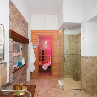 Mittelgroßes Landhaus Duschbad mit offenen Schränken, hellbraunen Holzschränken, Wandtoilette mit Spülkasten, beigefarbenen Fliesen, Waschtischkonsole, Glaswaschbecken/Glaswaschtisch, bodengleicher Dusche, Terrakottafliesen, weißer Wandfarbe und Terrakottaboden in Sonstige