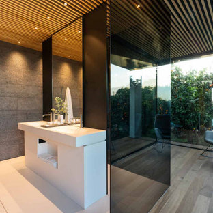 Ispirazione per una stanza da bagno moderna con ante bianche, piastrelle grigie, pavimento in legno massello medio, lavabo a consolle e pavimento marrone