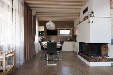 На фото: кухня-столовая среднего размера в современном стиле с бежевыми стенами, полом из керамогранита, фасадом камина из штукатурки и стандартным камином с