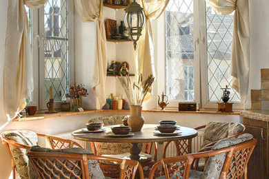 Пример оригинального дизайна: кухня-столовая среднего размера в средиземноморском стиле с белыми стенами, полом из керамогранита, стандартным камином, фасадом камина из камня и красным полом