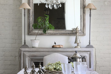 На фото: столовая в стиле шебби-шик с белыми стенами и стандартным камином с