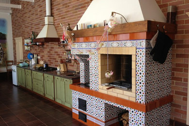 他の地域にある高級な中くらいなトラディショナルスタイルのおしゃれなダイニングキッチン (茶色い壁、セラミックタイルの床、標準型暖炉、タイルの暖炉まわり、茶色い床) の写真