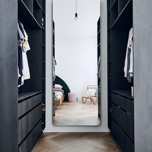 Inspiration for a contemporary walk-in wardrobe in Melbourne with flat-panel cabinets, black cabinets, medium hardwood floors and brown floor.