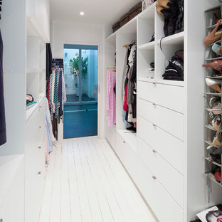 Réalisation d'un dressing design de taille moyenne et neutre avec un sol en bois peint, des portes de placard blanches, un placard à porte plane et un sol blanc.