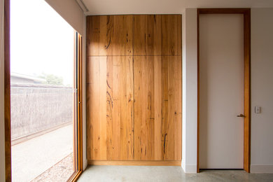Foto de armario vestidor actual grande con puertas de armario de madera oscura, suelo de cemento y suelo gris
