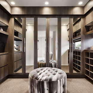 Esempio di uno spazio per vestirsi unisex design con ante lisce, ante in legno bruno, moquette e pavimento beige