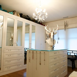 Modelo de vestidor de mujer, ecléctico, grande, con armarios estilo shaker, puertas de armario blancas y suelo de madera en tonos medios