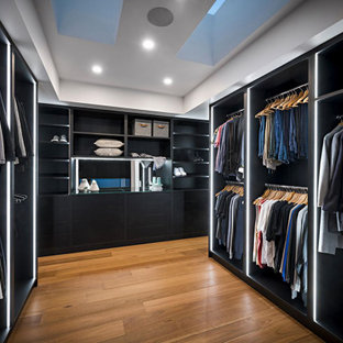 Esempio di un grande spazio per vestirsi unisex contemporaneo con nessun'anta, ante nere, pavimento in legno massello medio e soffitto ribassato