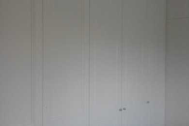Diseño de armario unisex tradicional con armarios con paneles empotrados y puertas de armario blancas