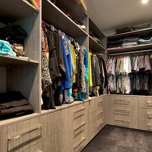 Modelo de armario vestidor unisex, minimalista, grande, con armarios con paneles lisos, puertas de armario de madera clara y moqueta