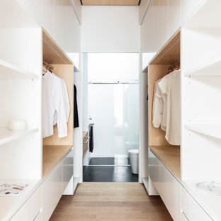 Foto di uno spazio per vestirsi unisex design con ante lisce, ante bianche, parquet chiaro e pavimento beige