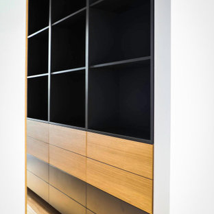 Esempio di una grande cabina armadio unisex design con ante nere, parquet chiaro e pavimento giallo