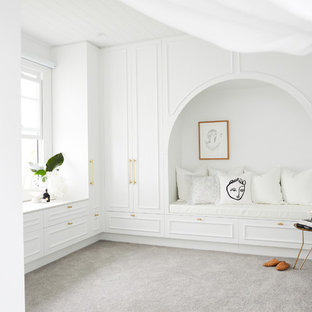 Design ideas for a large beach style gender-neutral walk-in wardrobe in Sydney with white cabinets, carpet, grey floor and recessed-panel cabinets.