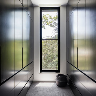 Idee per una cabina armadio unisex minimal di medie dimensioni con ante lisce, ante nere, moquette e pavimento grigio