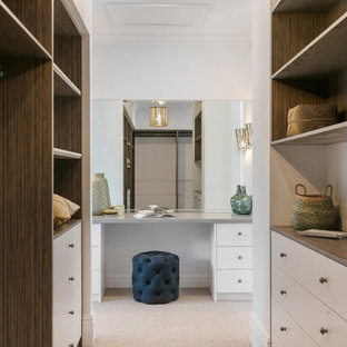 Foto de armario vestidor unisex, marinero, grande, con armarios abiertos, puertas de armario de madera oscura, moqueta y suelo beige