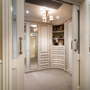 Klassisk inredning av ett stort walk-in-closet för könsneutrala, med luckor med infälld panel, skåp i slitet trä och heltäckningsmatta