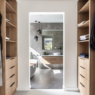 Diseño de armario vestidor unisex, moderno, pequeño, con puertas de armario de madera oscura, moqueta y suelo gris